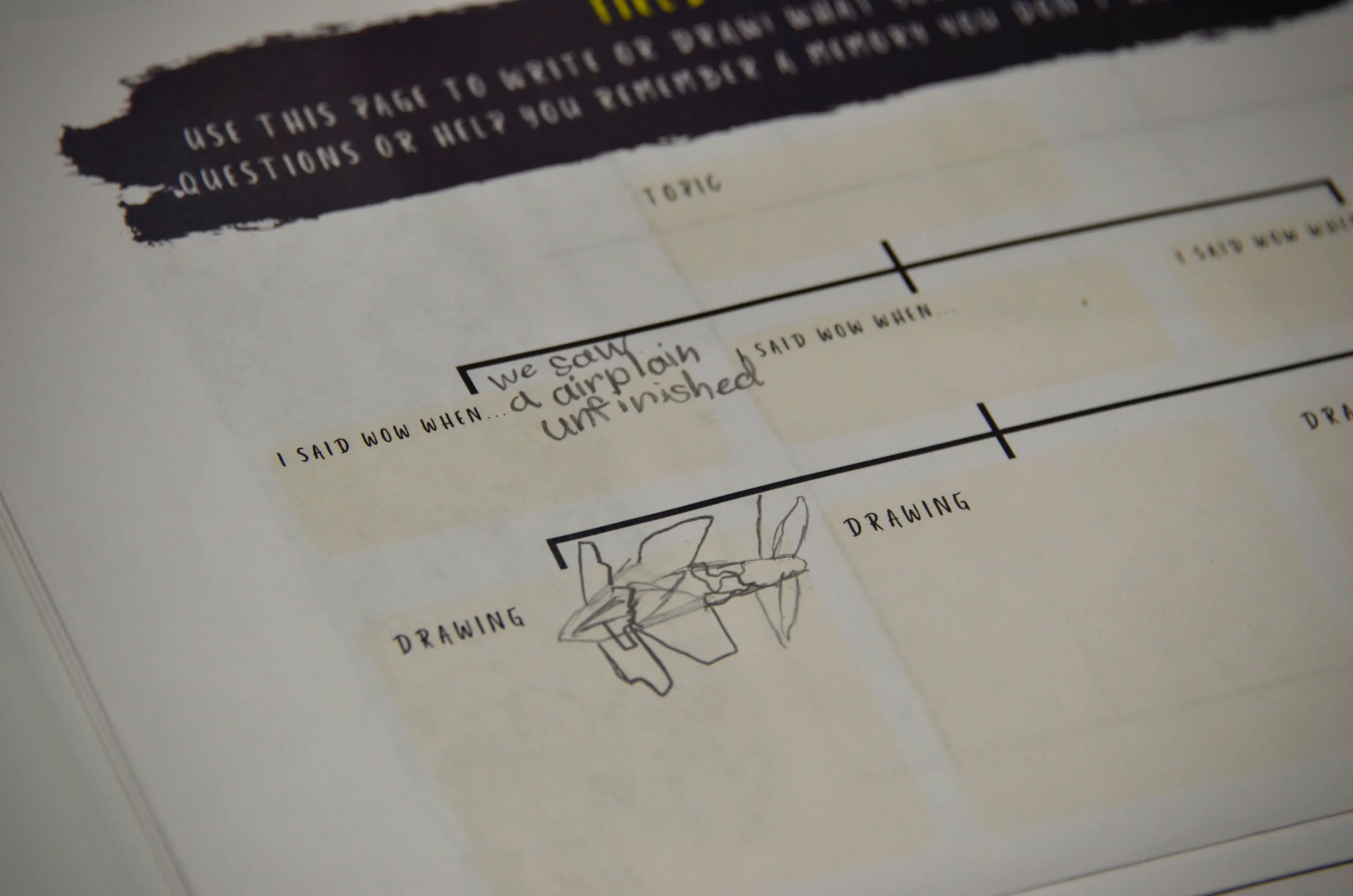 A close-up of a printed camp workbook page headed “I said WOW when…”, filled in by a child in pencil: “we saw a airplain unfinished”, with a hand-drawn aeroplane beneath it.